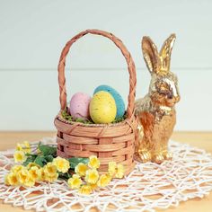 an easter basket with some eggs in it next to a golden rabbit statue on a doily