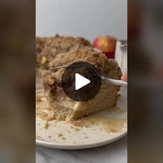 a piece of cake on a white plate with a fork in it and some apples