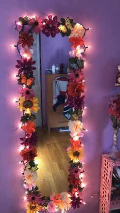 a mirror that has flowers on it and lights in the frame around it, along with other decorations