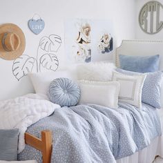 a bed with blue and white comforters in a bedroom next to pictures on the wall