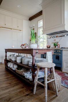 a kitchen filled with lots of white dishes and wooden furniture next to a stove top oven