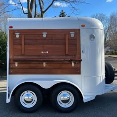 a white and brown truck parked on the side of a road next to a tree