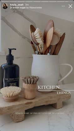 kitchen things displayed on wooden shelf in front of marbled wall and white vase with utensils