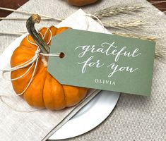 there is a small pumpkin sitting on a plate with a tag that says grateful for you