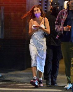 a woman in a white dress walking down the street