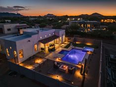 an aerial view of a house at night with lights on the patio and swimming pool