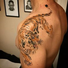 a man with a tiger tattoo on his back and chest is looking at the camera