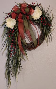 a wreath hanging on the wall with red and white flowers