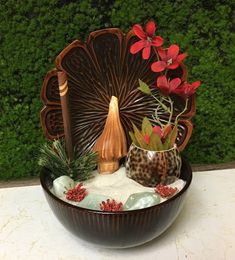 a bowl filled with sand and flowers on top of a table