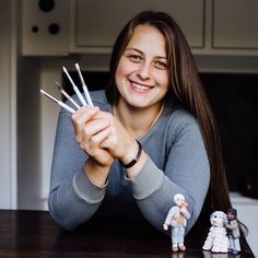 a woman sitting at a table with her fingers up in front of small figurines