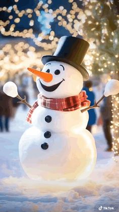 a snowman with a hat and scarf standing in the snow next to a christmas tree