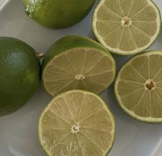 limes cut in half on a white plate with one whole lime and four pieces