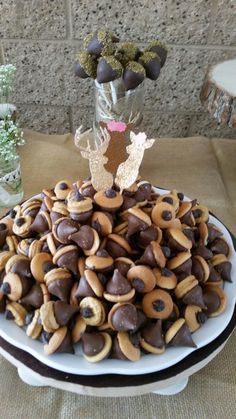 a plate full of chocolate covered pretzels on a table with flowers in the background