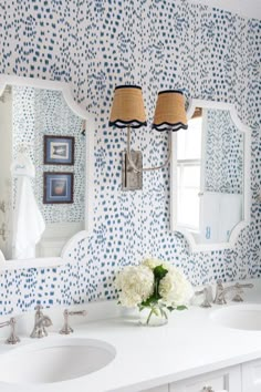 a bathroom with blue and white wallpaper, two sinks and three mirrors on the wall