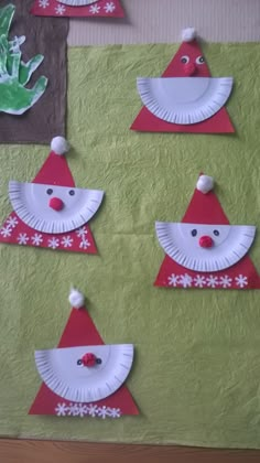 some paper plates with santa hats on them and snowflakes hanging from the wall