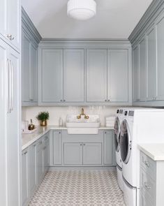 a laundry room with grey cabinets and white counter tops, along with a washer and dryer