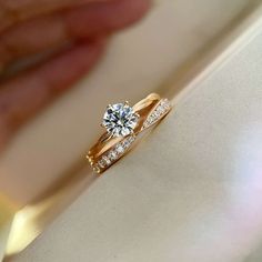 a close up of a person's hand holding a diamond ring