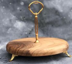 a small wooden stand with a gold ring on it's end and a key hanging from the top