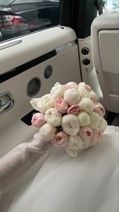 a bouquet of flowers sitting on top of a white cloth covered seat in the back of a car