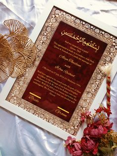 the wedding card is on display next to some red flowers and gold fan shaped decorations