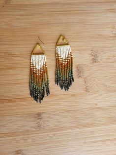 two pairs of beaded earrings sitting on top of a wooden table