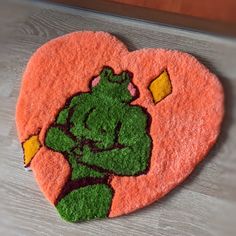 a heart shaped rug with an image of a green man holding a yellow object in the shape of a heart