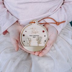 a person holding a christmas ornament in their hands with the words till first christmas written on it