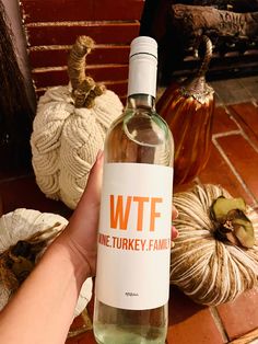 a hand holding a bottle of wftf wine next to pumpkins