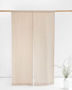 two white vases sitting next to each other on top of a table with an open curtain