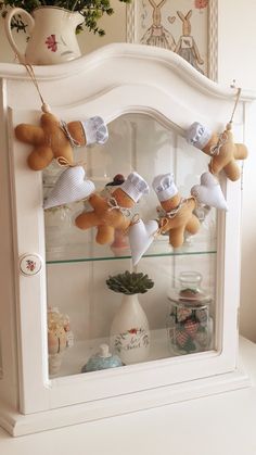 a display case filled with stuffed animals on top of a white shelf next to a potted plant