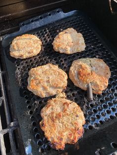 four hamburger patties cooking on an outdoor grill