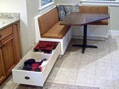 a bench with drawers underneath it in a kitchen next to a table and counter top