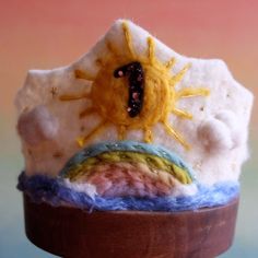 a close up of a cup with a knitted sun on it