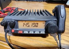 an old radio sitting on top of a wooden table next to a charger and wires