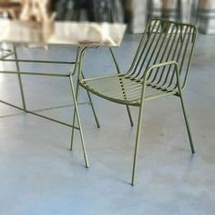 two green chairs sitting next to each other on top of a cement floor in front of a glass table