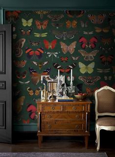 a chair sitting next to a dresser in front of a wall with butterflies on it