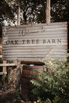 a wooden sign that reads welcome to oak tree barn in front of some bushes and trees