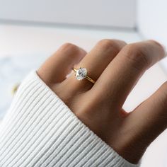 a woman's hand with a diamond ring on top of her finger, in front of a white background