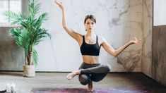 a woman is doing yoga in front of a marble wall and potted palm tree