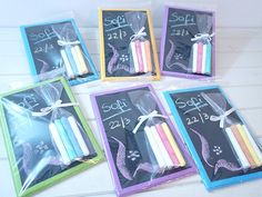 six packaged candles in cello bags on a white wooden table with chalk writing and ribbon