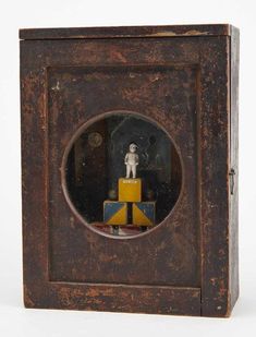 an old wooden box with a small figurine in it's center window