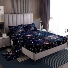 a bed room with a neatly made bed and a night sky print on the comforter