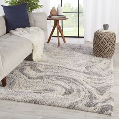 a living room area with a couch, rug and coffee table in front of a window