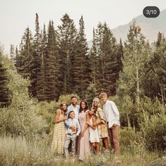 a family poses for a photo in front of some tall pine trees with the mountains behind them