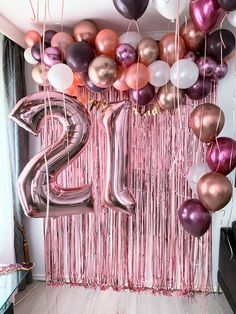 balloons and streamers are hanging from the ceiling in front of a number twenty sign