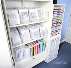 a white bookcase filled with lots of books and boxes on top of it's shelves