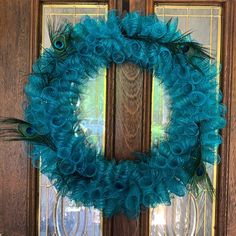 a blue wreath with feathers hanging on the front door to decorate it for someone's special occasion