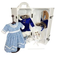 two dolls are dressed in blue and white outfits, one is holding a doll's hand