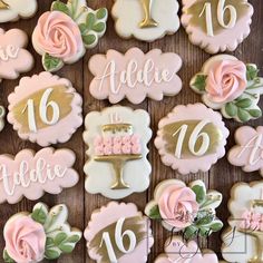 decorated cookies with pink and gold icing are arranged on a wooden surface, including the number 16