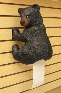 a statue of a bear holding a piece of paper in it's mouth on a wall